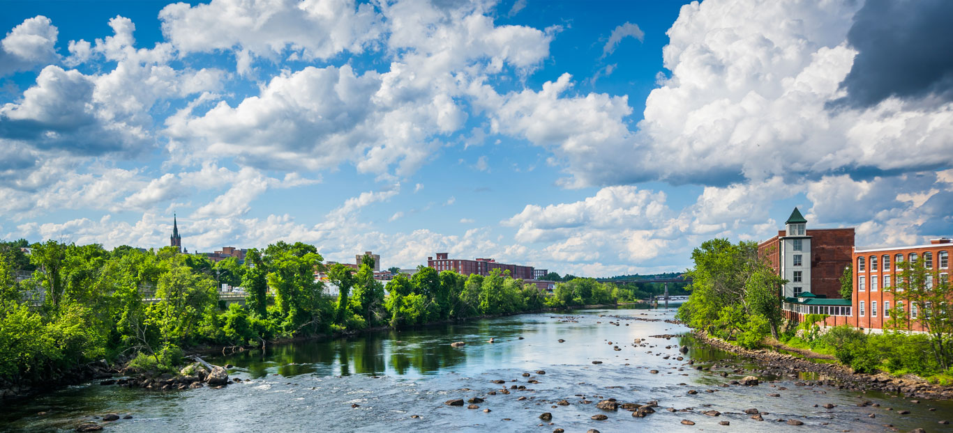 RIver with trees on the left side and brick buildings on its right side